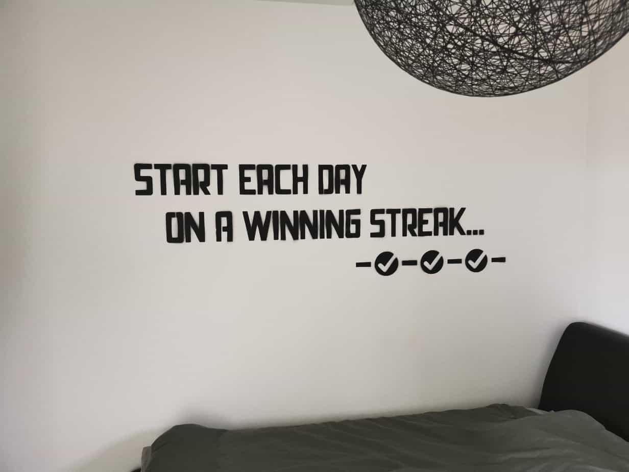 Wall lettering in Danny's bedroom reading 'Start each day on a winning streak' above three ticked checkmarks.