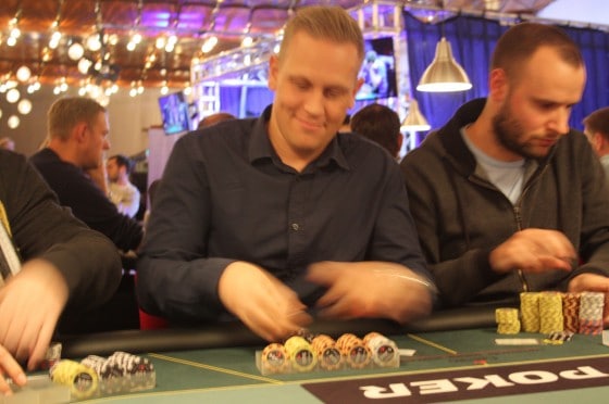 Danny grinning as he stacks chips at a live poker table.